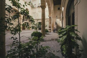 Ein Innenhof mit Steinböden, Säulen und Topfpflanzen.