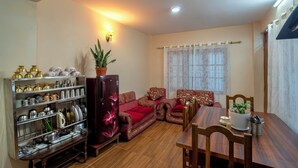 Ein Wohnzimmer mit Sofa, Esstisch, Kühlschrank und einer Küchenzeile mit Geschirr.