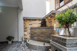 A courtyard with a stone wall, a statue, and potted plants. - Serenova Apartment,  Modern 2BHK, Valley View (Kathmandu)