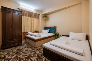 Ein Hotelzimmer mit zwei Betten, einem Schrank, einem gemusterten Boden und einer kleinen Pflanze.