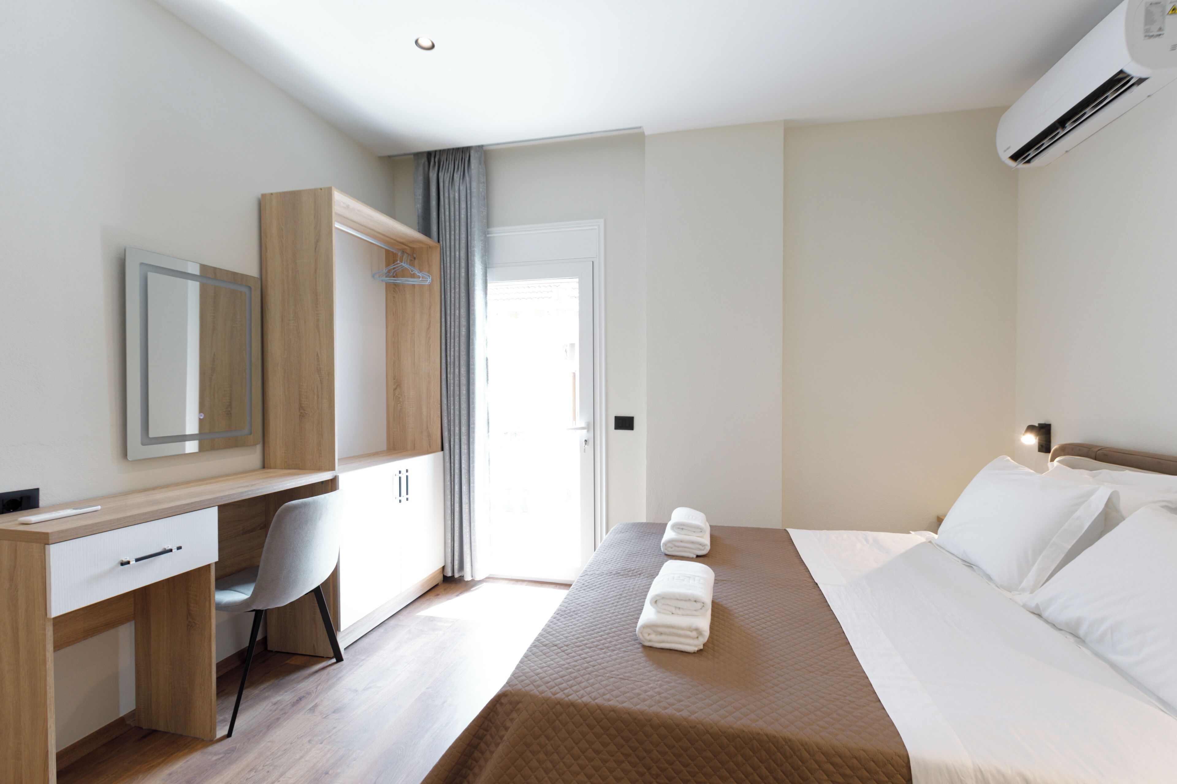 Ein Hotelzimmer mit Bett, Schreibtisch, Stuhl, Kleiderschrank und Klimaanlage.