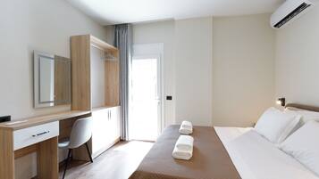 Ein Hotelzimmer mit Bett, Schreibtisch, Stuhl, Kleiderschrank und Klimaanlage.