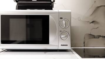 A microwave oven with a digital display and control knobs, placed on a white countertop.