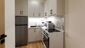 Una cucina compatta con frigorifero, fornello, microonde e forno integrati.