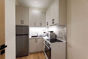 Uma cozinha compacta com geladeira, fogão, micro-ondas e forno embutidos.
