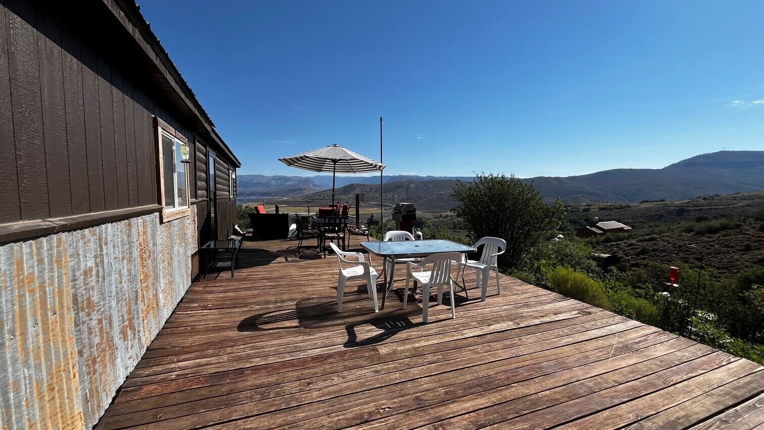 A wooden deck with outdoor furniture and a view of a mountainous landscape.