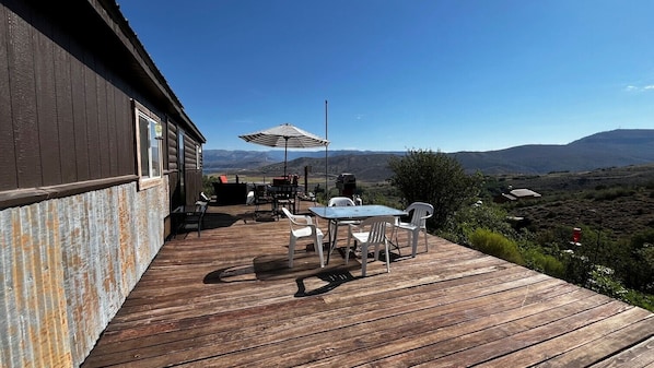 A wooden deck with outdoor furniture and a view of a mountainous landscape.