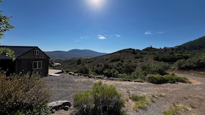 Una cabaña rústica con camino de grava y vista a un paisaje montañoso.