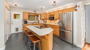 Una cocina moderna con una isla central, electrodomésticos de acero inoxidable, armarios de madera y un microondas integrado.