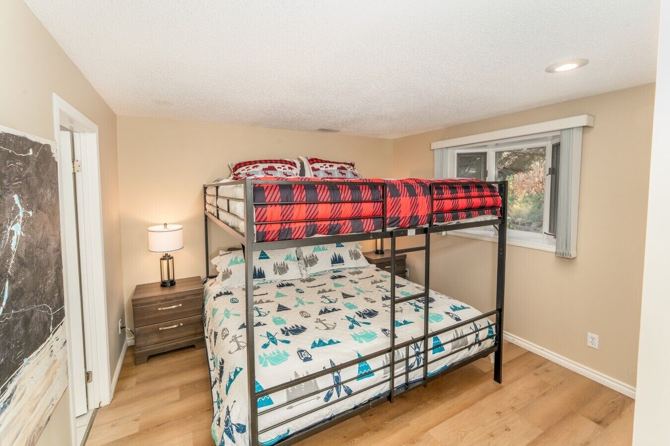 A bunk bed with a red and black patterned top bunk and a lower bunk with a blue and white mountain design.