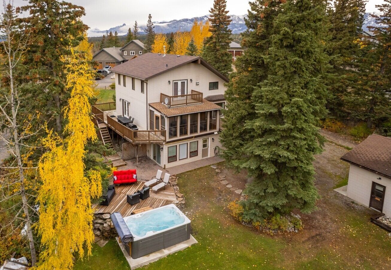 A two-story house with a deck, a hot tub, and a fenced yard.