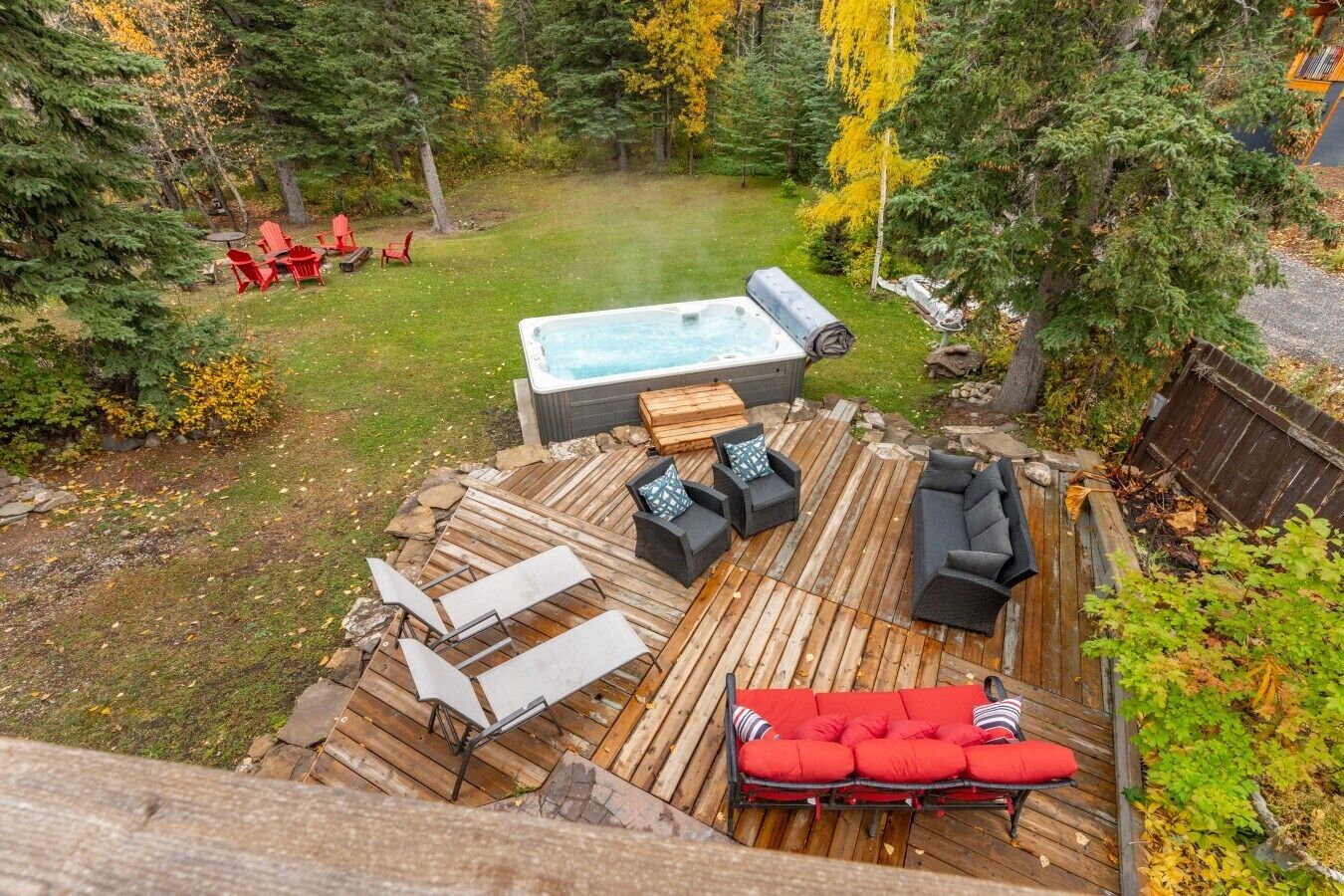 Un bain à remous entouré de meubles de jardin sur une terrasse en bois.