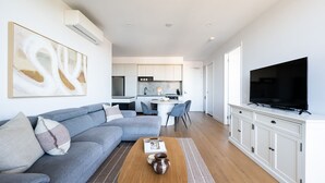 Un salon moderne avec un canapé gris, une table basse et un téléviseur à écran plat.