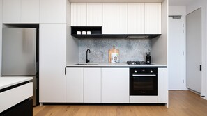 Een moderne keuken met een geïntegreerde koelkast, een Bosch oven en een aanrecht met een spoelbak en fornuis.