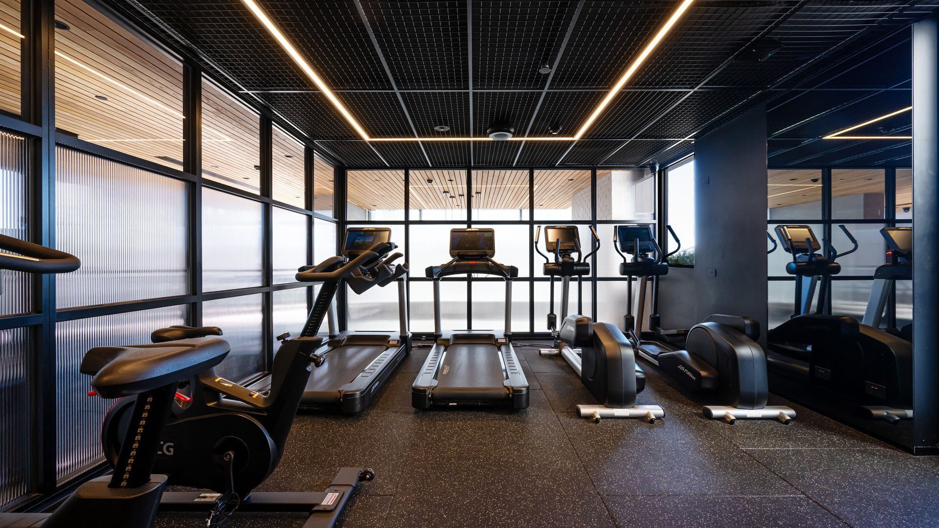 A modern gym with treadmills, elliptical machines, and stationary bikes.