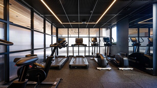 Une salle de sport moderne équipée de tapis de course, d’appareils elliptiques et de vélos d’appartement.