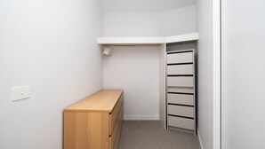 Un petit dressing sans porte, avec un banc en bois, un plafond blanc et une étagère intégrée.