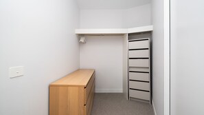 A small walk-in closet with a wooden bench, a white ceiling, and a built-in shelving unit. - The Foundry by Property Mums (Burwood East)