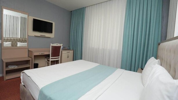 A hotel room with a bed, a desk, a chair, a television, and curtains. - Alis Hotel Baku (Baku)