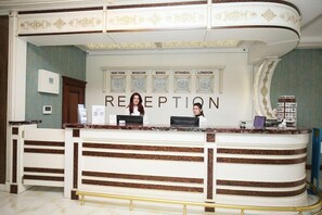 Una reception con una bacheca che elenca città come New York, Mosca, Baku, Istanbul e Londra.
