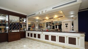 A bar area with a marble countertop, shelves with bottles, and a decorative ceiling. - Alis Hotel Baku (Baku)