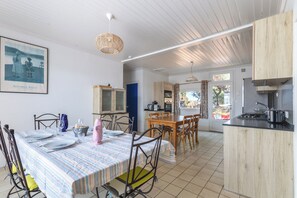 Ein Essbereich mit Tisch für vier Personen, eine Küche mit Holzschränken und ein Speisezimmer mit Blick ins Freie.