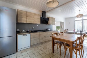 A modern kitchen with a built-in oven, a refrigerator, and wooden cabinets. - La Linière - Proche plage - Petfriendly (Noirmoutier-en-l'Île)