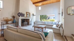 Ein Wohnzimmer mit Kamin, einer Couch, einem Couchtisch und einem Fenster mit Blick auf Grünflächen.