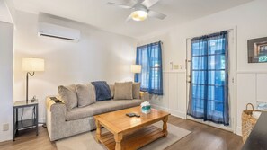 Ein Wohnzimmer mit einer Couch, einem Couchtisch, einer Lampe und einem Fenster mit Vorhängen.