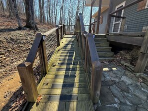 A wooden bridge leading to a building with a stone foundation.
