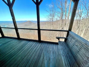 A wooden deck with a bench, overlooking a mountainous landscape.