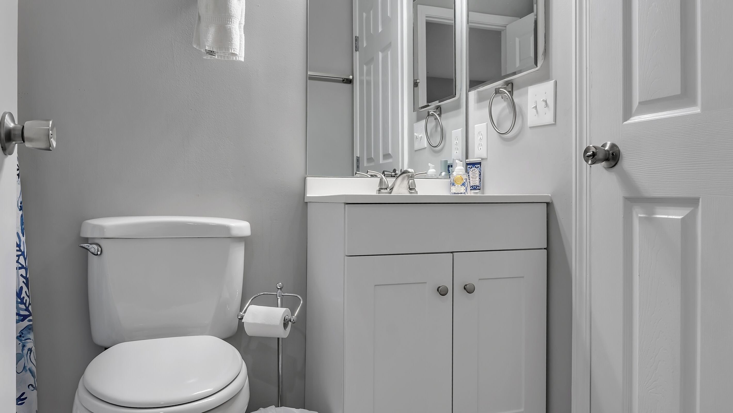 Une salle de bain comprenant des toilettes, un lavabo avec un miroir au-dessus et un meuble en dessous.