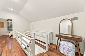 Ein Zimmer mit einem weißen Schminktisch, einem Spiegel und einer Bank.