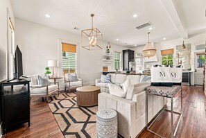 A spacious living area with a sofa set, a coffee table, and a TV on a stand. - Historic Galveston Cottage | Walk to the Beach (Galveston)