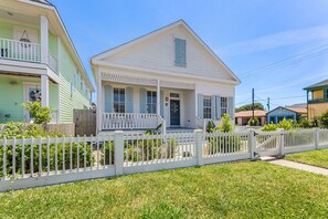 A two-story house with a porch and a white picket fence. - Historic Galveston Cottage | Walk to the Beach (Galveston)