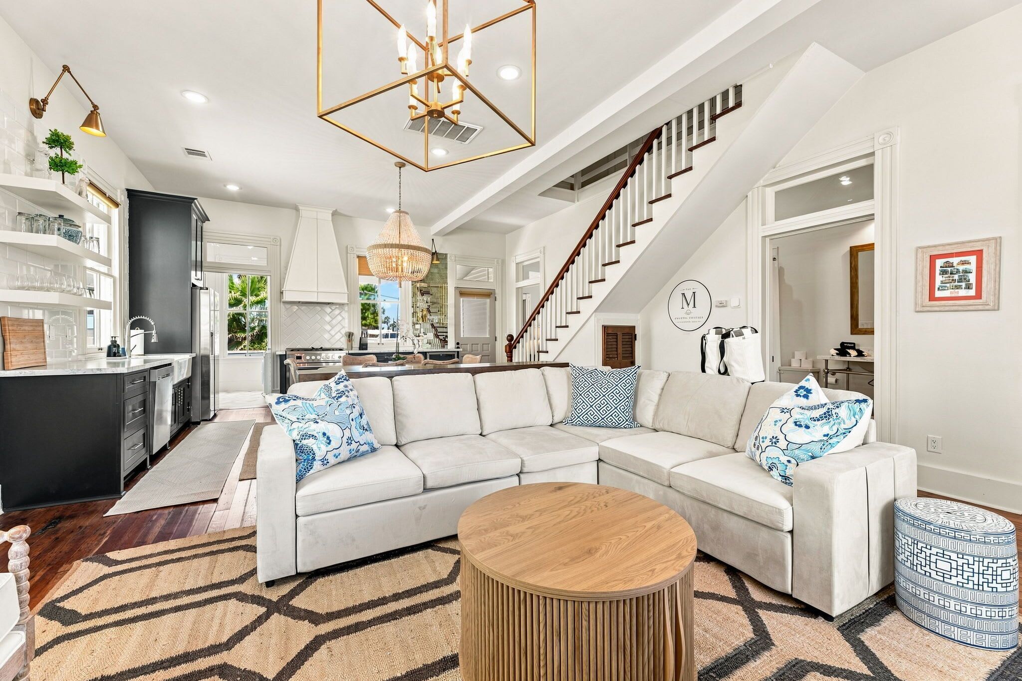 A modern living room with a sectional sofa, a round coffee table, and a staircase leading to the upper floor.