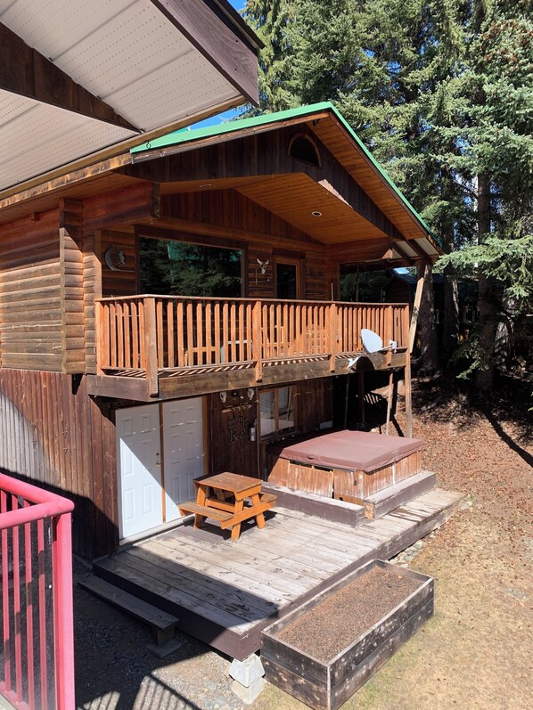 A wooden cabin with a balcony, a picnic table, and a covered outdoor seating area.