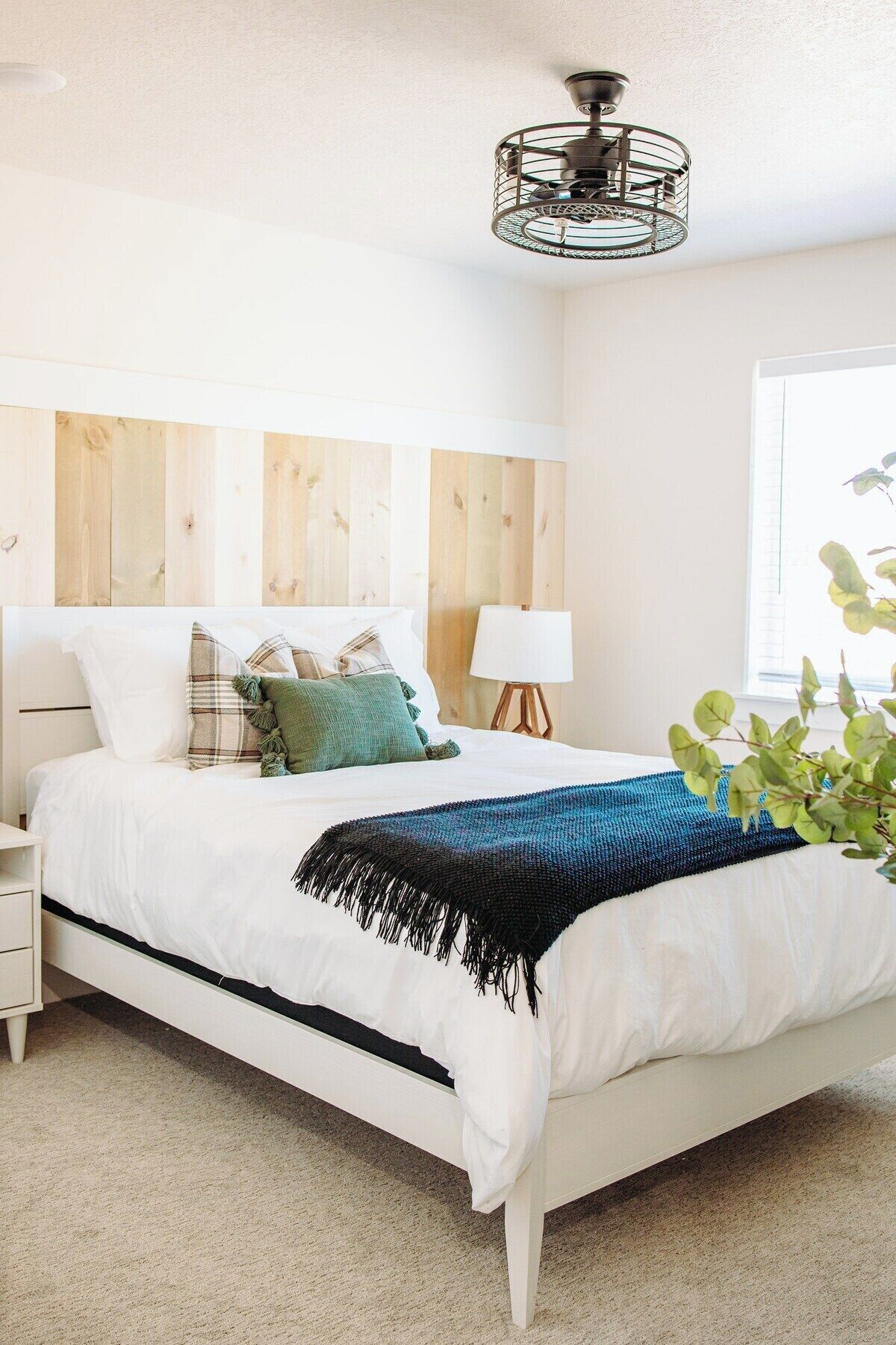 A bedroom with a bed, nightstand, lamp, and a ceiling fan.