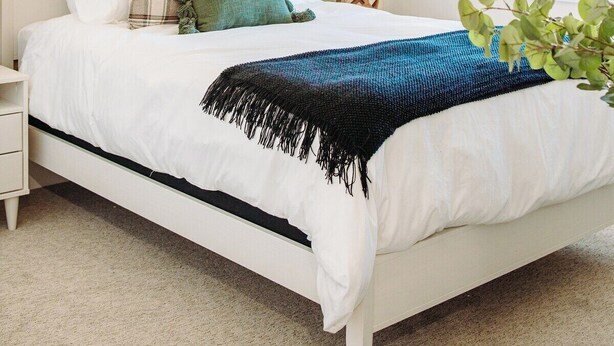Un dormitorio con cama, mesita de noche, lámpara y ventilador de techo.