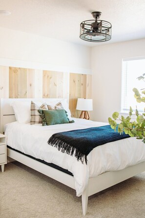 Un dormitorio con cama, mesita de noche, lámpara y ventilador de techo.