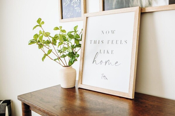 A framed sign with text, a potted plant, and a wooden table.