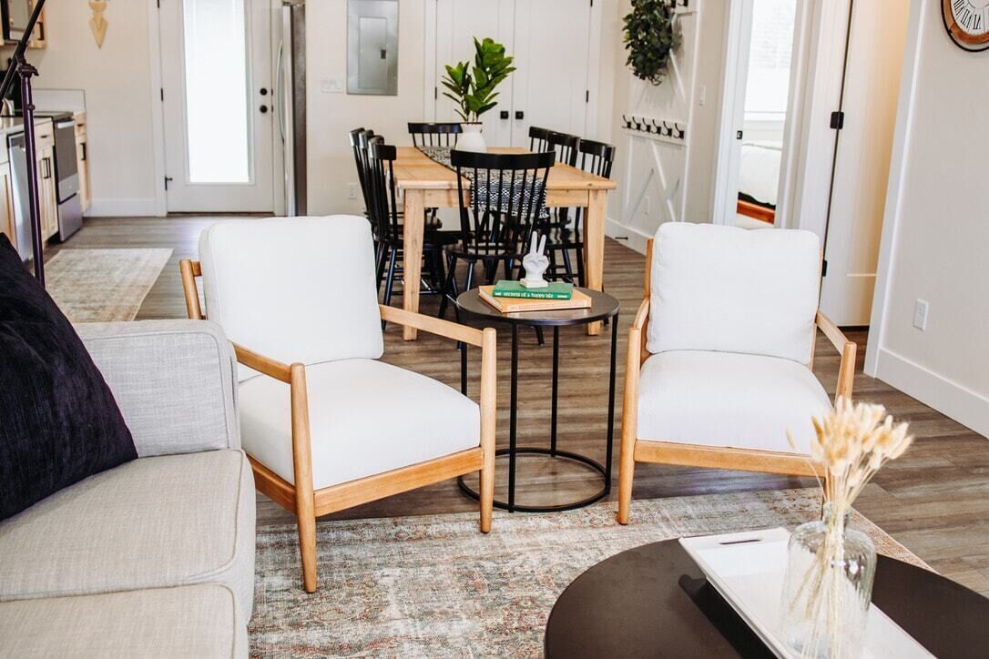 Ett modernt vardagsrum med en soffa, två fåtöljer, ett soffbord och ett matbord med stolar.
