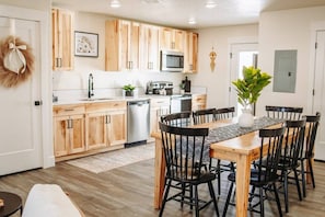 Una cocina moderna con armarios de madera, una mesa de comedor con sillas y un microondas.