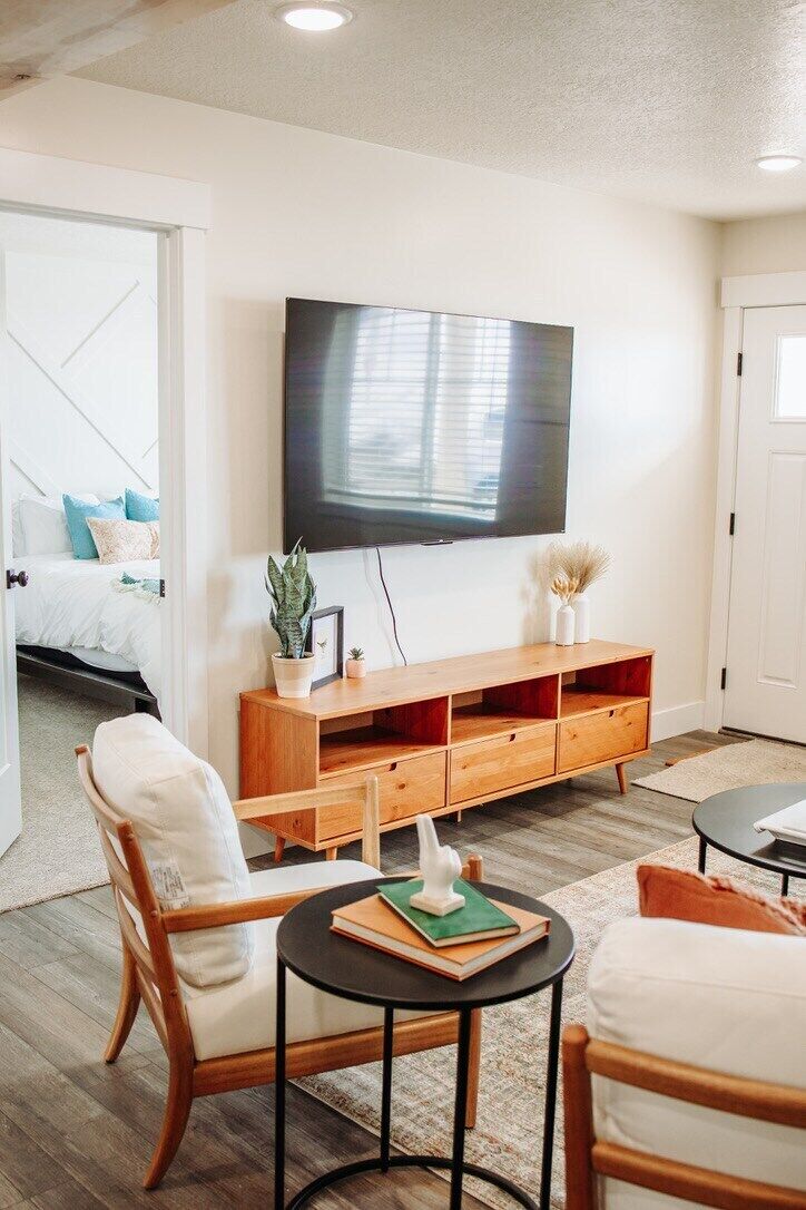 A modern living room with a flat-screen TV, wooden entertainment unit, and comfortable seating.