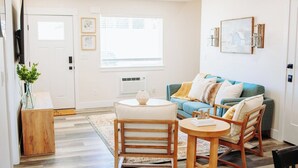 Una sala de estar con sofá, dos sillones, una mesa de centro y televisor.