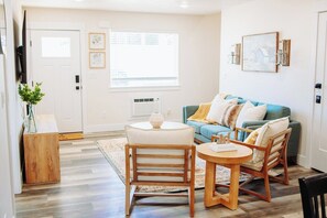 Un salon comprenant un canapé, deux fauteuils, une table basse et un téléviseur.