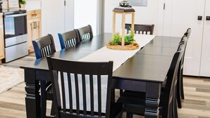 Una cocina moderna con armarios de madera, una isla central y un comedor con una mesa larga y sillas.
