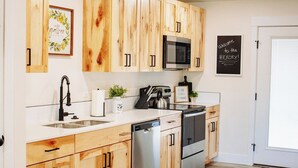 Una cocina moderna con gabinetes de madera, electrodomésticos de acero inoxidable y encimera blanca.