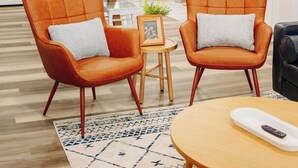 Eine moderne Küche mit Holzausstattung, eine Essecke mit orangefarbenen Stühlen und ein Wohnbereich mit einer Couch.