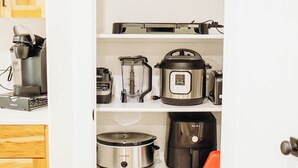 Eine Küche mit Holzausstattung, einer Kaffeemaschine, einem Mixer, einem Slow-Cooker und einem Toaster.